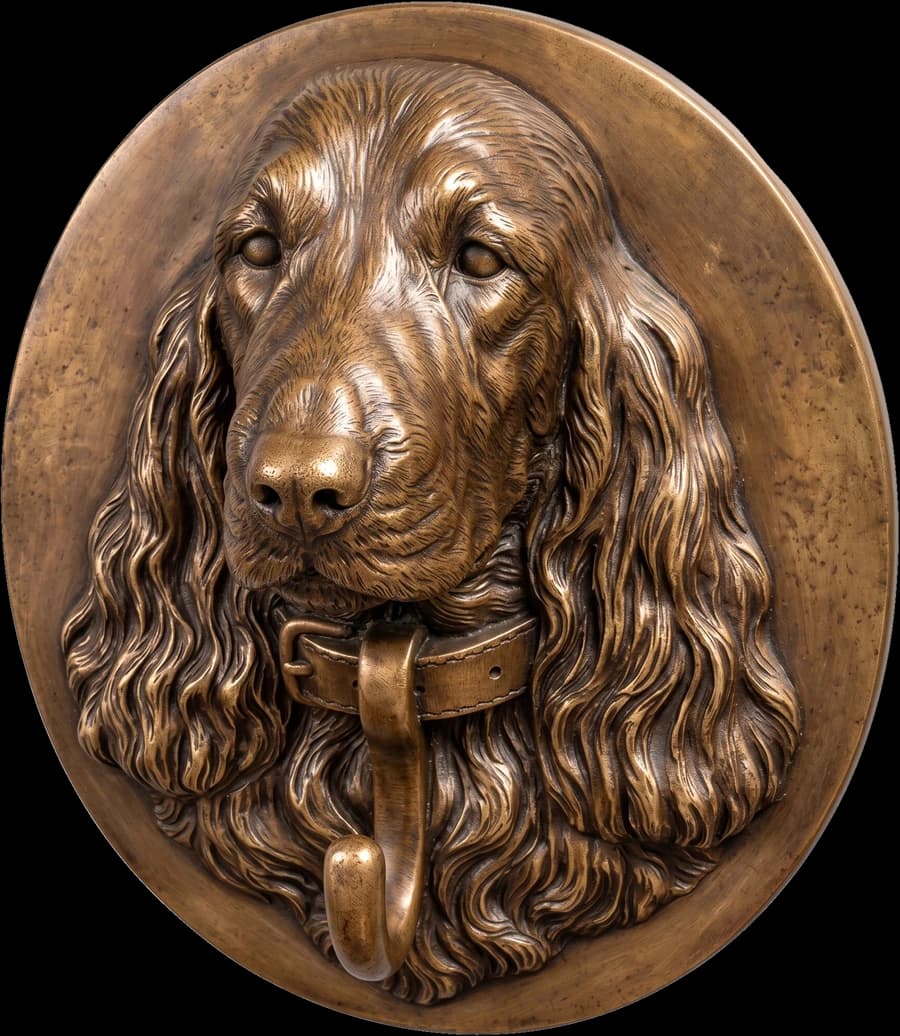 A cocker spaniel wall mount in a bronze finish, the dog's head in relief on an oval plaque with a hook for the lead below